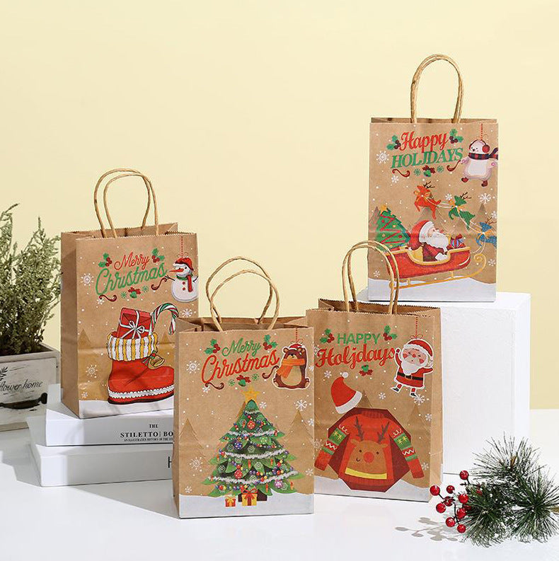 Four festive paper gift bags with Christmas designs, including Santa, snowmen, and decorated trees, arranged on a white surface with a pine branch accent.