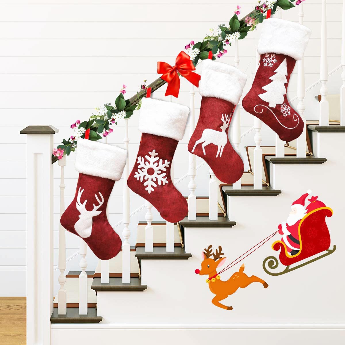 Four red Christmas stockings with white patterns hang on a staircase garland. A Santa and reindeer decal decorates the stairs.