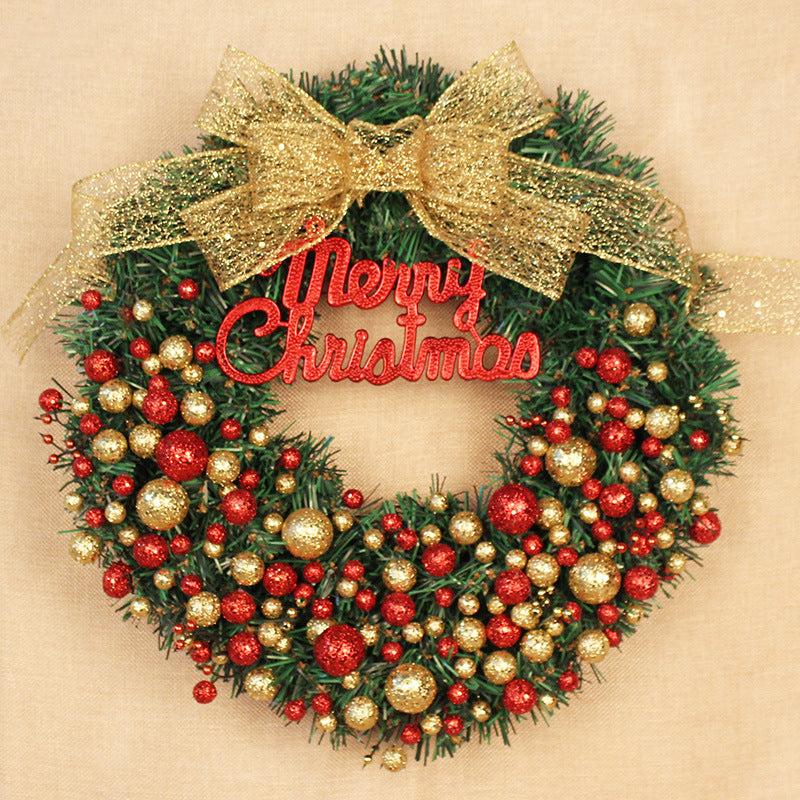 A festive Christmas wreath adorned with red and gold ornaments, featuring a glittery gold bow on top and a "Merry Christmas" sign at the center.