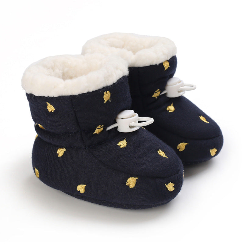 Navy blue baby booties with white fleece lining, gold leaf embroidery, and white toggle fasteners.