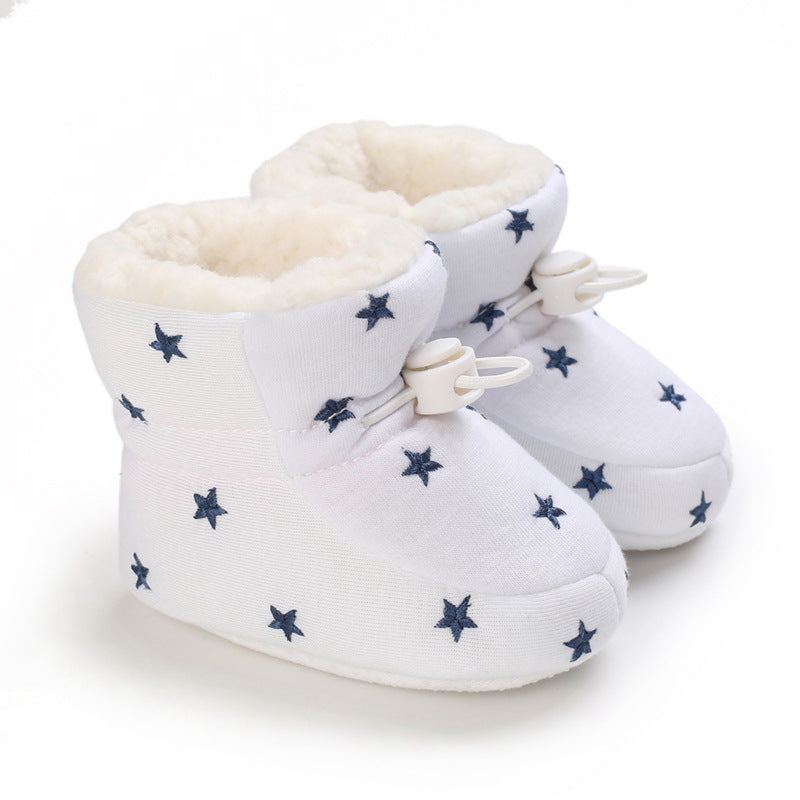 White baby booties with navy star patterns, featuring a soft, plush interior and adjustable toggle clasps on the front.