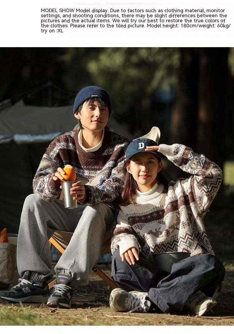 A man and woman sitting outdoors in matching patterned sweaters and winter hats, enjoying a sunny day. The man is holding an orange and a cup, while the woman shields her eyes.