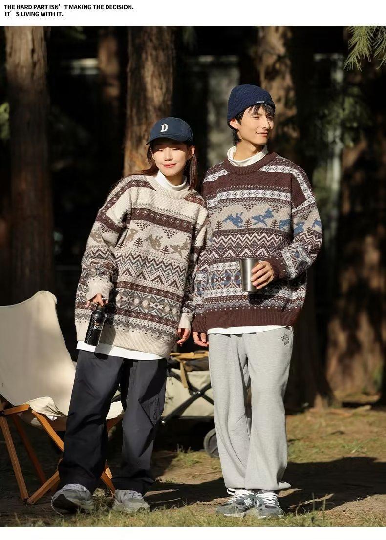 Young couple in matching patterned sweaters and casual attire, standing outdoors. She holds a bottle, he holds a cup. Sunny day with trees in the background.