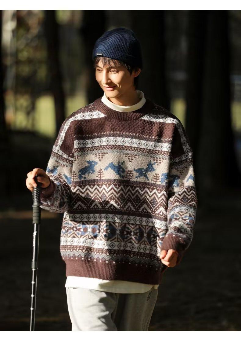 Young man walking in the forest, wearing a patterned brown sweater and dark blue beanie, casually holding a walking stick, with sunlight illuminating his face.