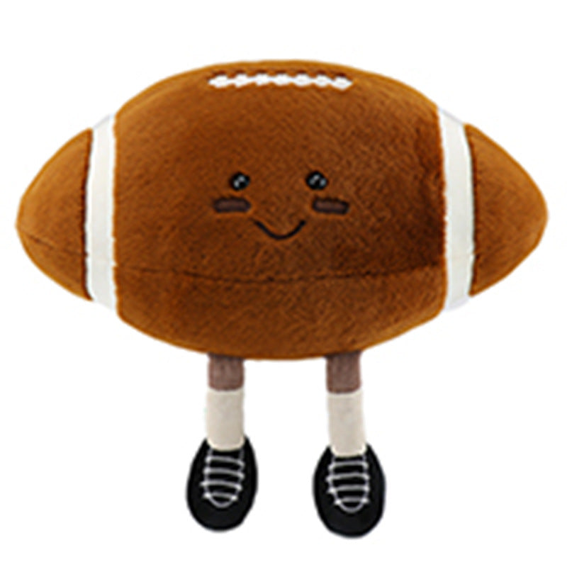 A plush football toy with a smiley face, featuring stitched details, white stripes, and wearing black shoes. The football has short legs and is light brown in color.