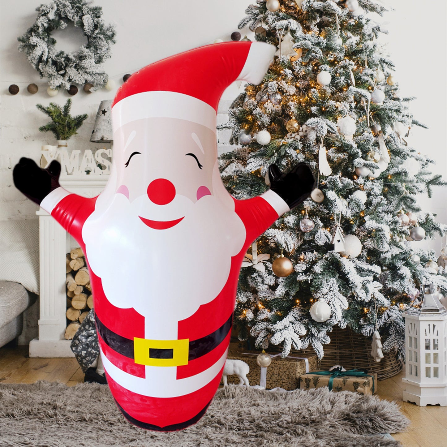 Festive indoor scene with an inflatable Santa, smiling and waving, standing on a fuzzy rug. A decorated Christmas tree with white and gold ornaments twinkles in the background.