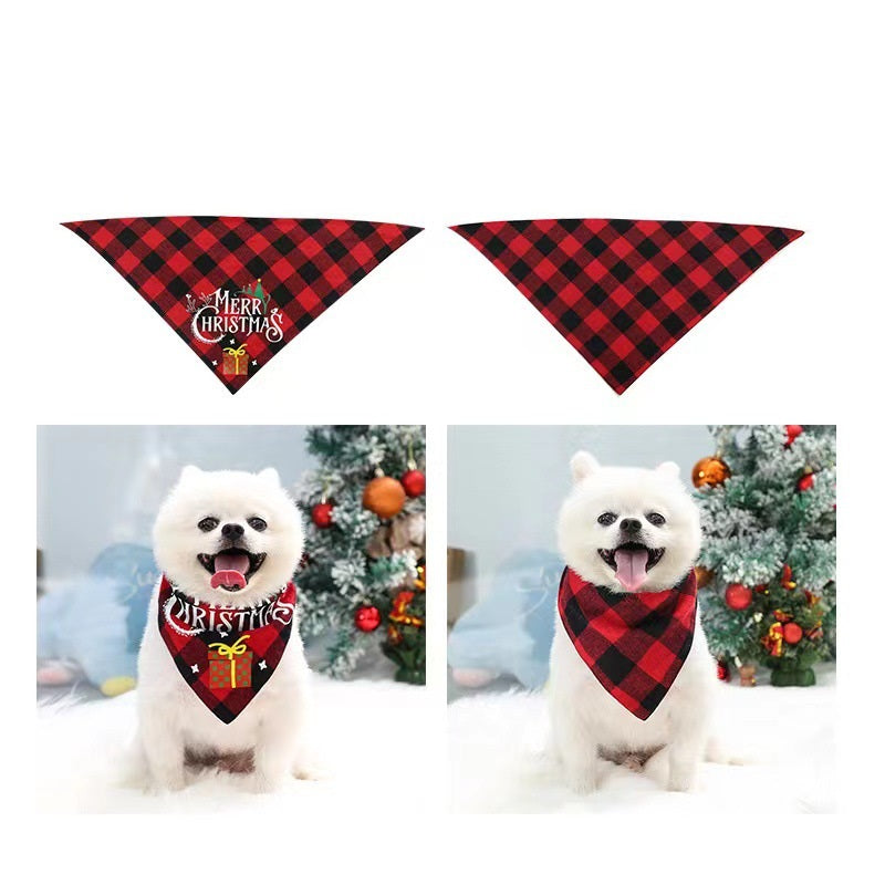 White dog wearing a red and black plaid bandana, one with "Merry Christmas" text and gift design. The dog is sitting in front of a decorated Christmas tree.