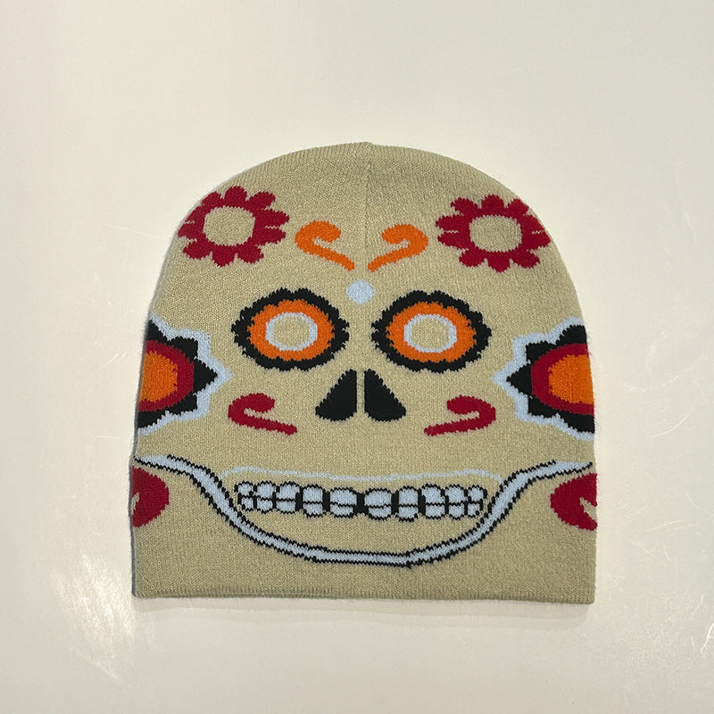 A beige beanie featuring a colorful, stylized sugar skull design with vibrant orange, red, and black details, resembling traditional Day of the Dead art.