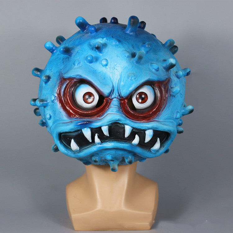 A blue, angry virus-shaped mask with red-rimmed eyes and sharp teeth, mounted on a mannequin bust against a gray background.