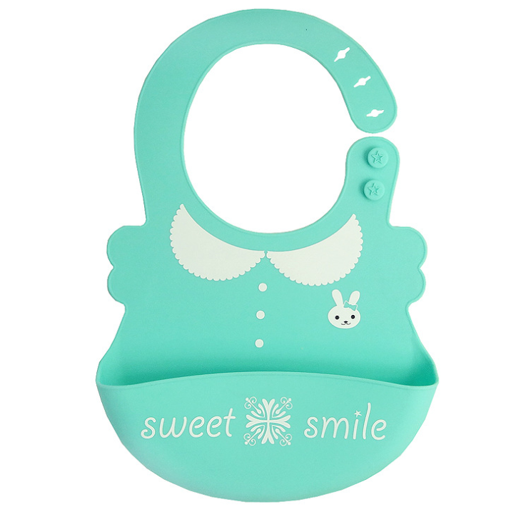 Turquoise silicone baby bib with a scalloped collar design, bunny face, and enclosed pocket. Features adjustable neck strap with star buttons and "sweet smile" text on the pocket.