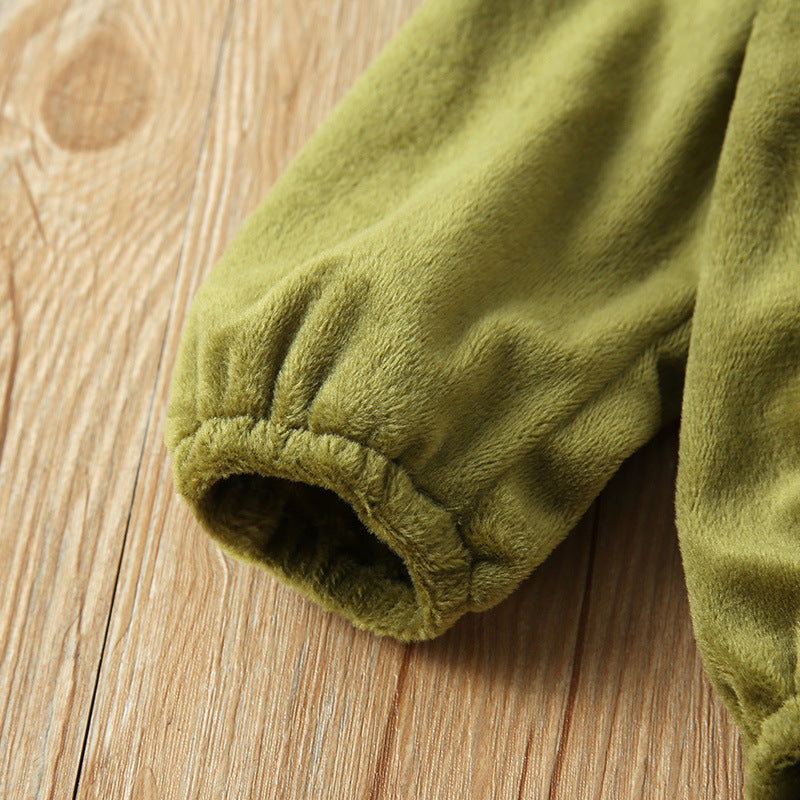 Close-up of a green, plush sleeve with elastic cuff lying on a textured wooden surface, showcasing the soft fabric and detailed stitching.