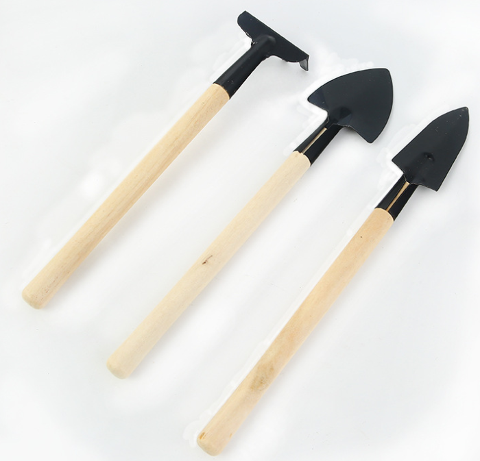 Three small garden tools with wooden handles; a mini hoe, a shovel, and a spade, arranged on a white background.
