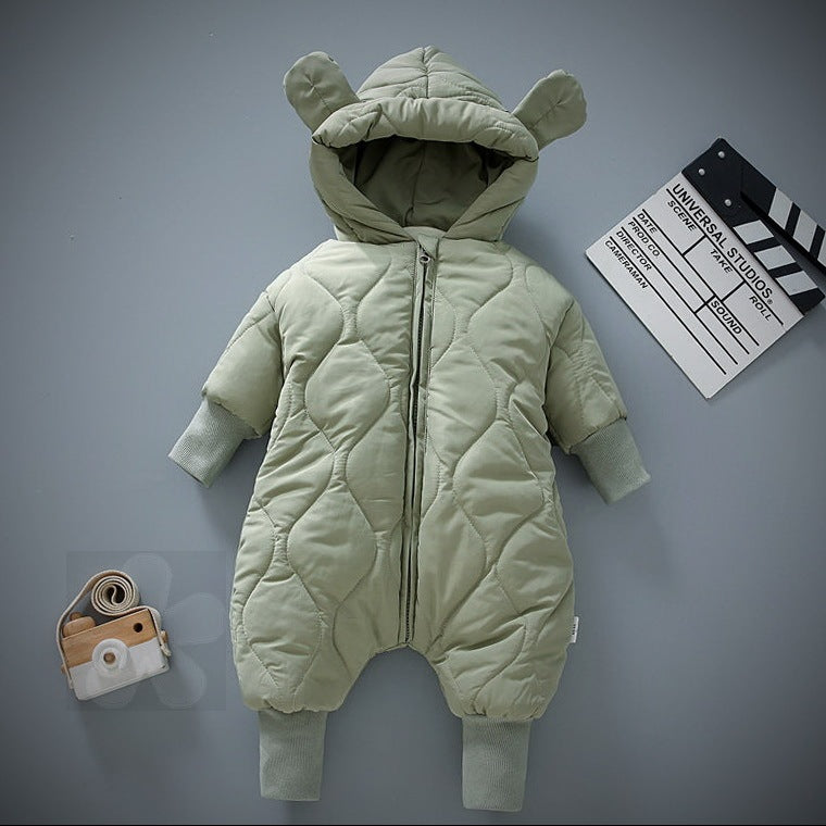 Light green quilted baby snowsuit with hood and teddy bear ears, laid flat. Nearby, a small toy camera and a movie clapperboard on a gray background.