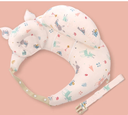 A baby neck pillow shaped like an animal with ears, featuring a colorful, playful pattern of animals and trees, on a pink background. A matching beige strap is included.
