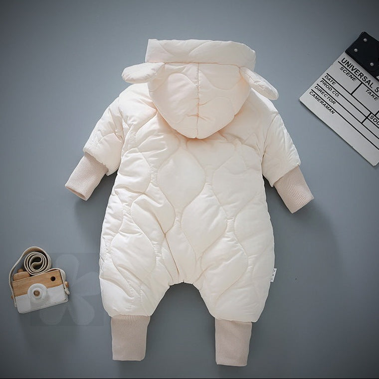 Cream-colored baby snowsuit with hood and ear details, laid flat on a gray surface. Next to it is a toy camera and a slate board labeled "Universal."