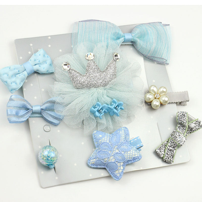 A collection of light blue and silver hair accessories on a gray star-patterned card. Includes bows, a glittery crown, a star, pearl flower clip, and a decorative ball.