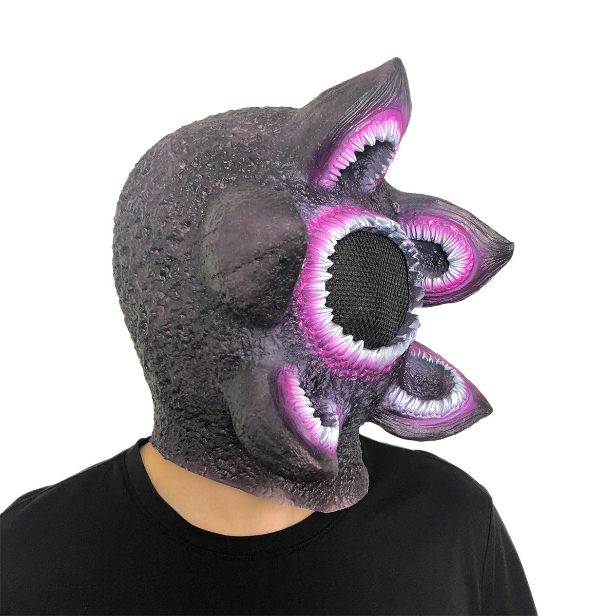 Person wearing a textured, alien-themed mask with multiple gaping mouths and white-pinkish teeth. The mask is mostly purple with a rough, bumpy surface.
