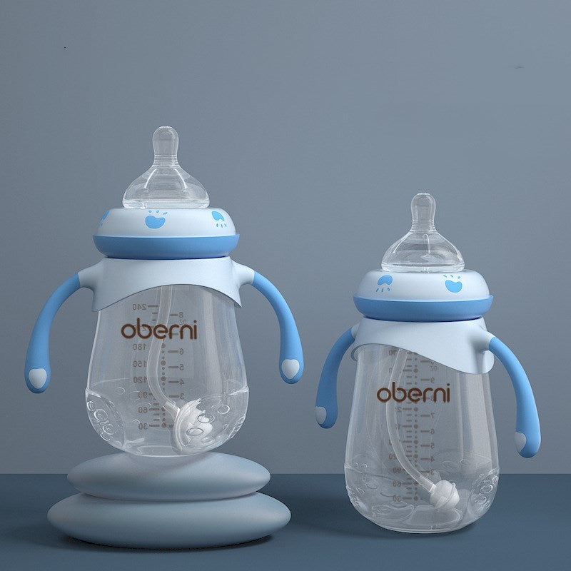 Two transparent baby bottles with blue handles and lids, featuring measurement markings. One is on a grey stand, both have clear nipples and small blue designs on the lids.