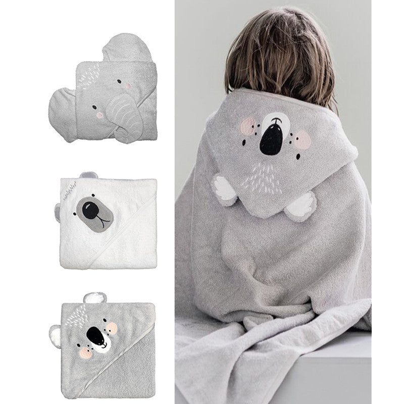 A child wears a gray hooded towel featuring a koala design. Next to the child, three folded towels with animal faces: an elephant, a polar bear, and another koala.