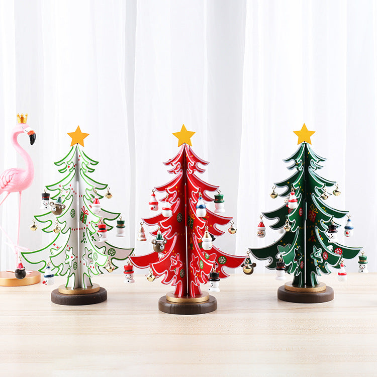 Three decorative Christmas trees in white, red, and green with yellow stars and ornaments. A pink flamingo with a crown stands to the left. White curtain backdrop.