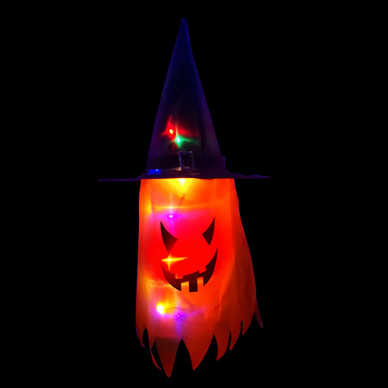 A glowing Halloween decoration of a carved pumpkin face with a pointed witch hat. Multicolored lights illuminate the face, creating a spooky effect against the dark background.