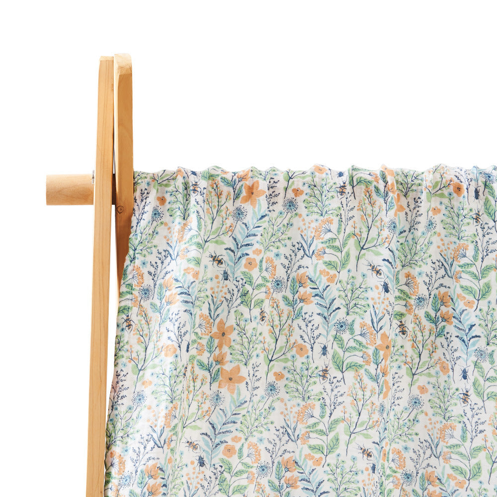 Floral fabric with orange and blue flowers on a white background, draped over a wooden frame.