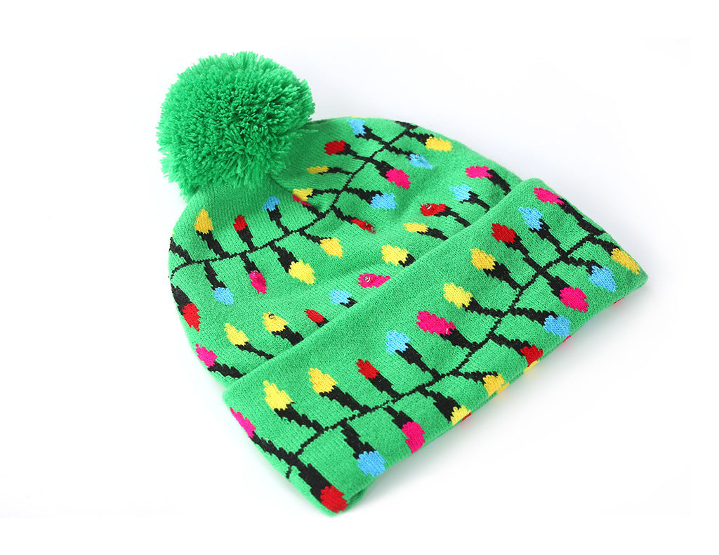 Green beanie with a large pom-pom, adorned with colorful holiday light patterns in red, yellow, blue, and pink, creating a festive and playful look.