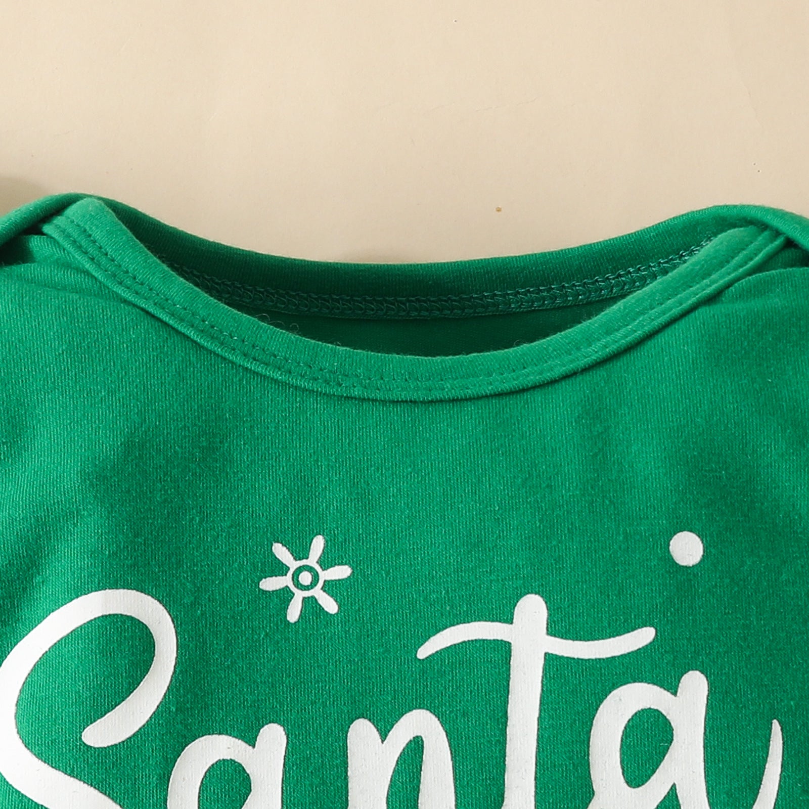 Green T-shirt with white lettering partially visible, displaying the beginning of the word "Santa." The shirt features a simple round neckline.