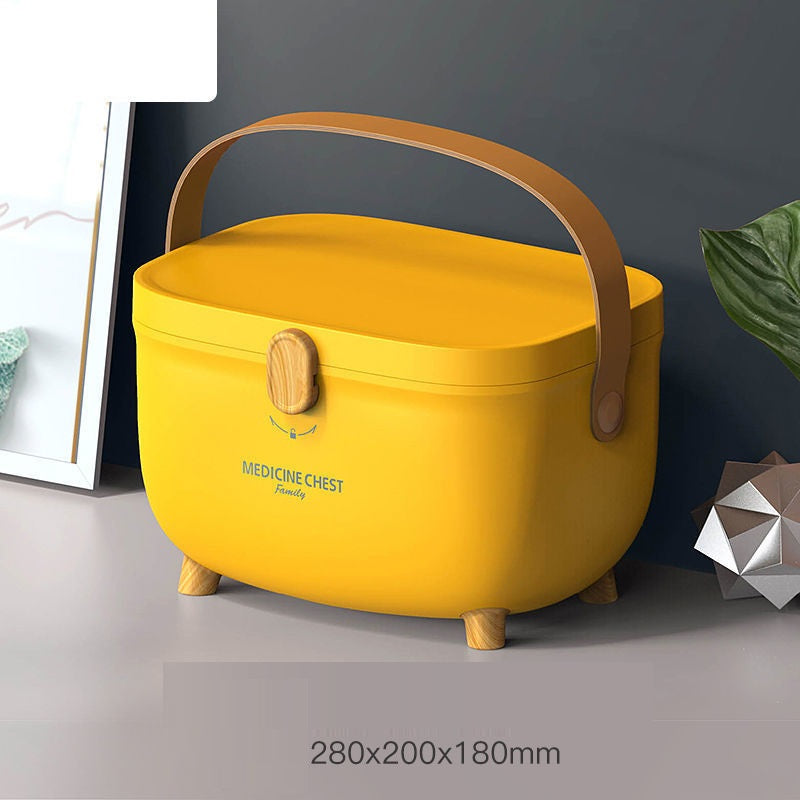 Yellow medicine chest with a wooden clasp and handle, set on short legs. The image includes decorative elements nearby and dimensions 280x200x180mm printed on it.