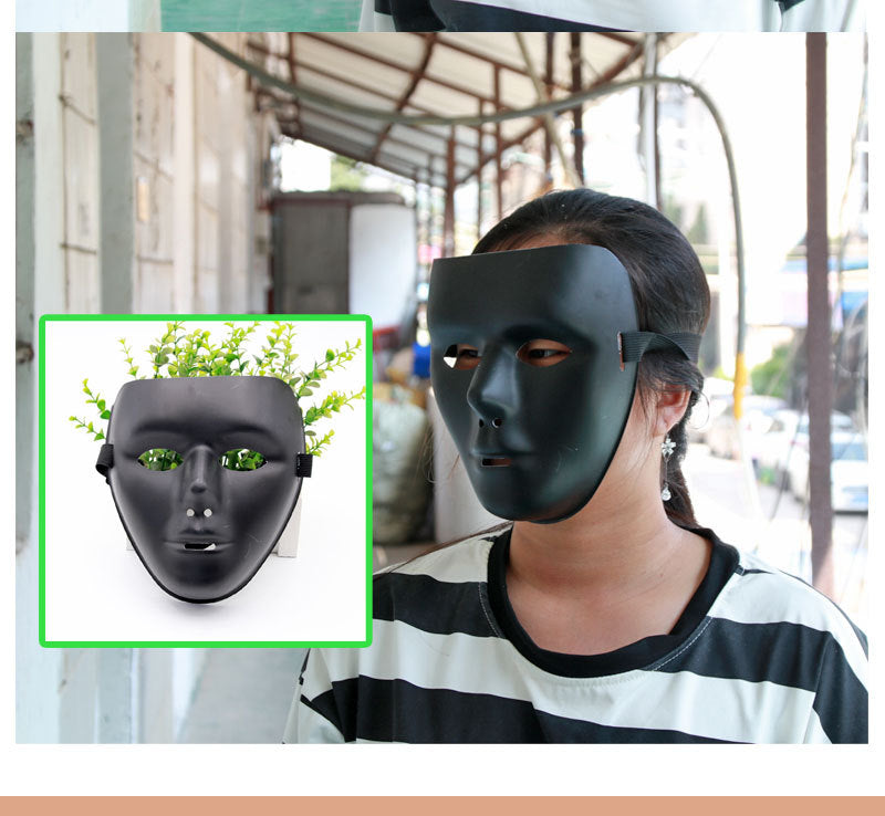 A person wearing a black mask with a plant background displayed in an inset. The mask has plant-like designs on the eyes, and the person is standing in an industrial setting.