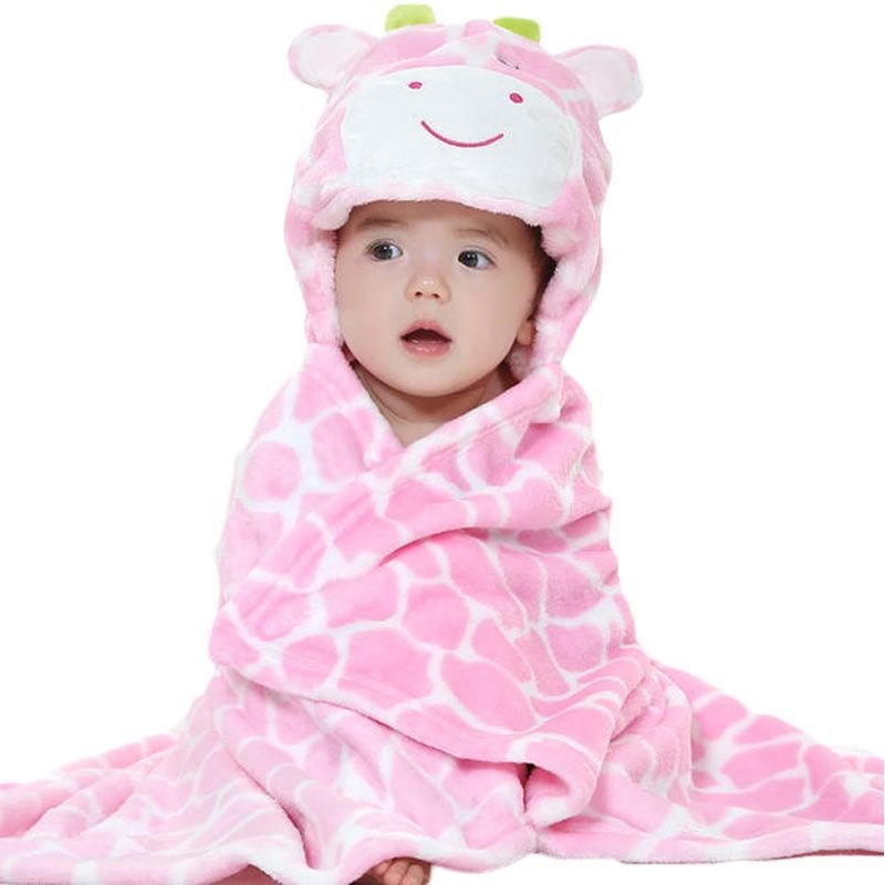 Baby wrapped in a pink giraffe-patterned blanket with matching hood, sitting and looking forward with curious expression. The blanket has a cute face design on the hood.