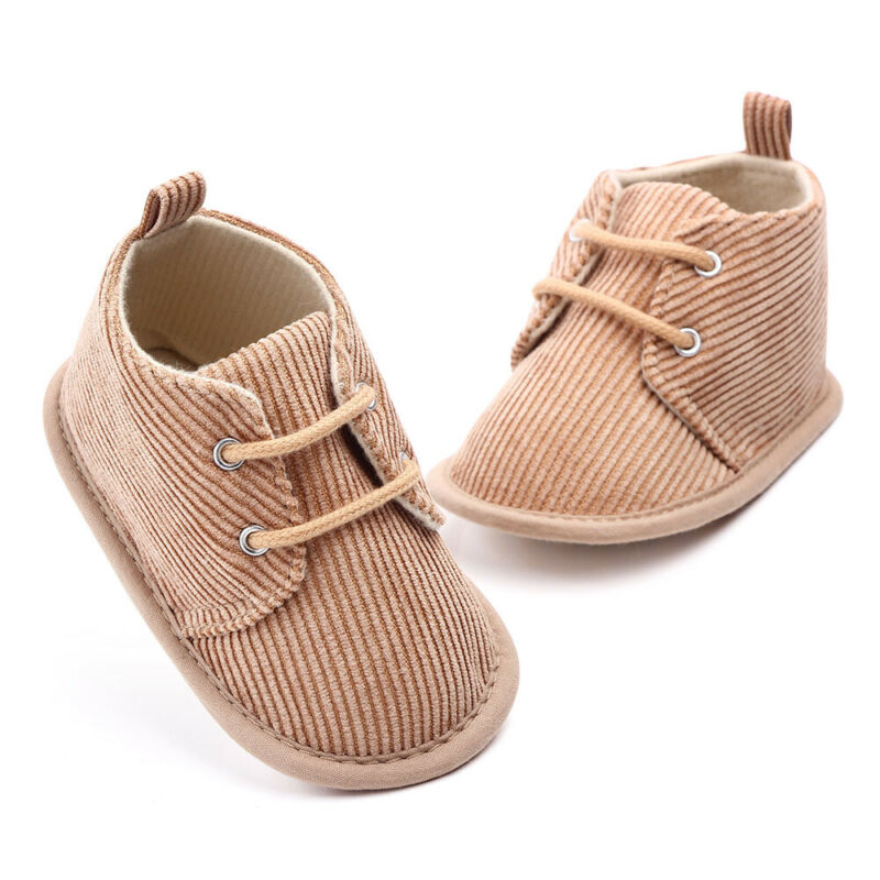 Brown baby shoes with a corduroy texture, featuring laces and soft soles. Displayed on a plain white background, the shoes appear cozy and stylish, ideal for infants.
