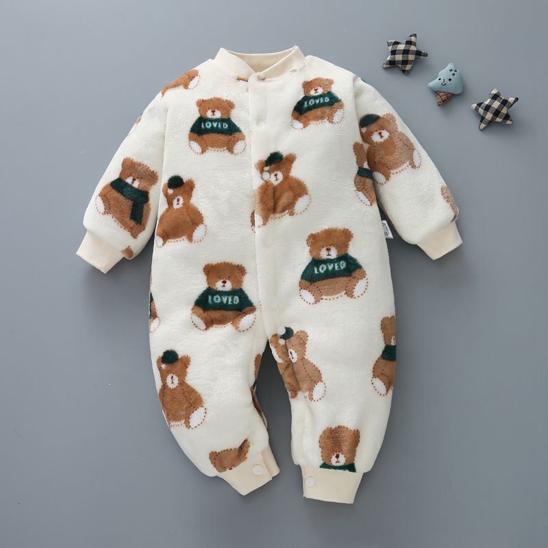 Cream-colored baby jumpsuit with cute teddy bear print wearing green "Loved" sweaters, laid on a gray background with three small decorative toys on the side.