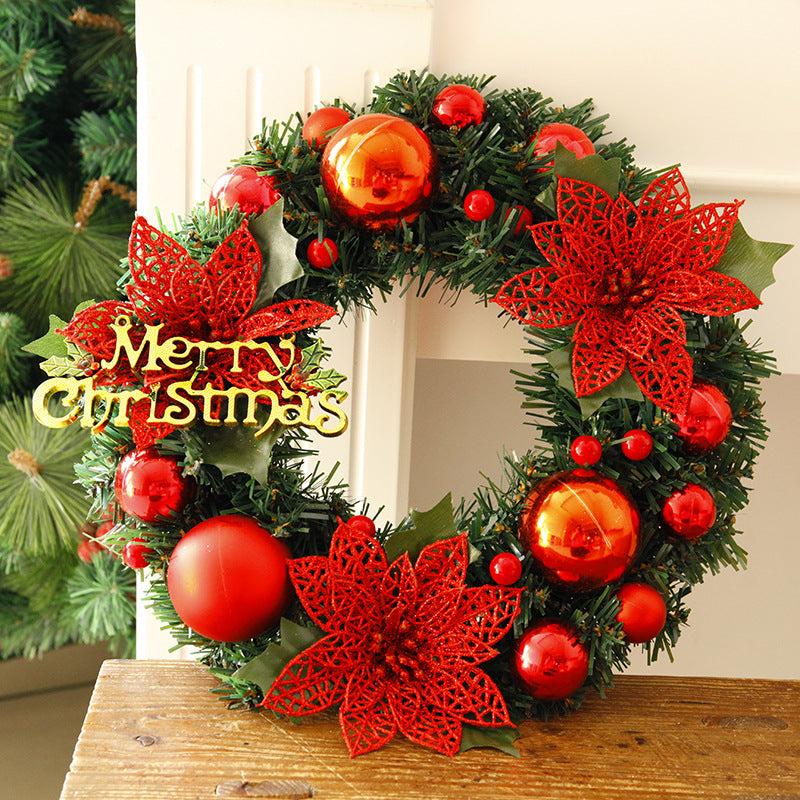 Festive Christmas wreath with red baubles, poinsettia flowers, and a "Merry Christmas" sign. The wreath features lush greenery and holiday decorations, set against a light background.