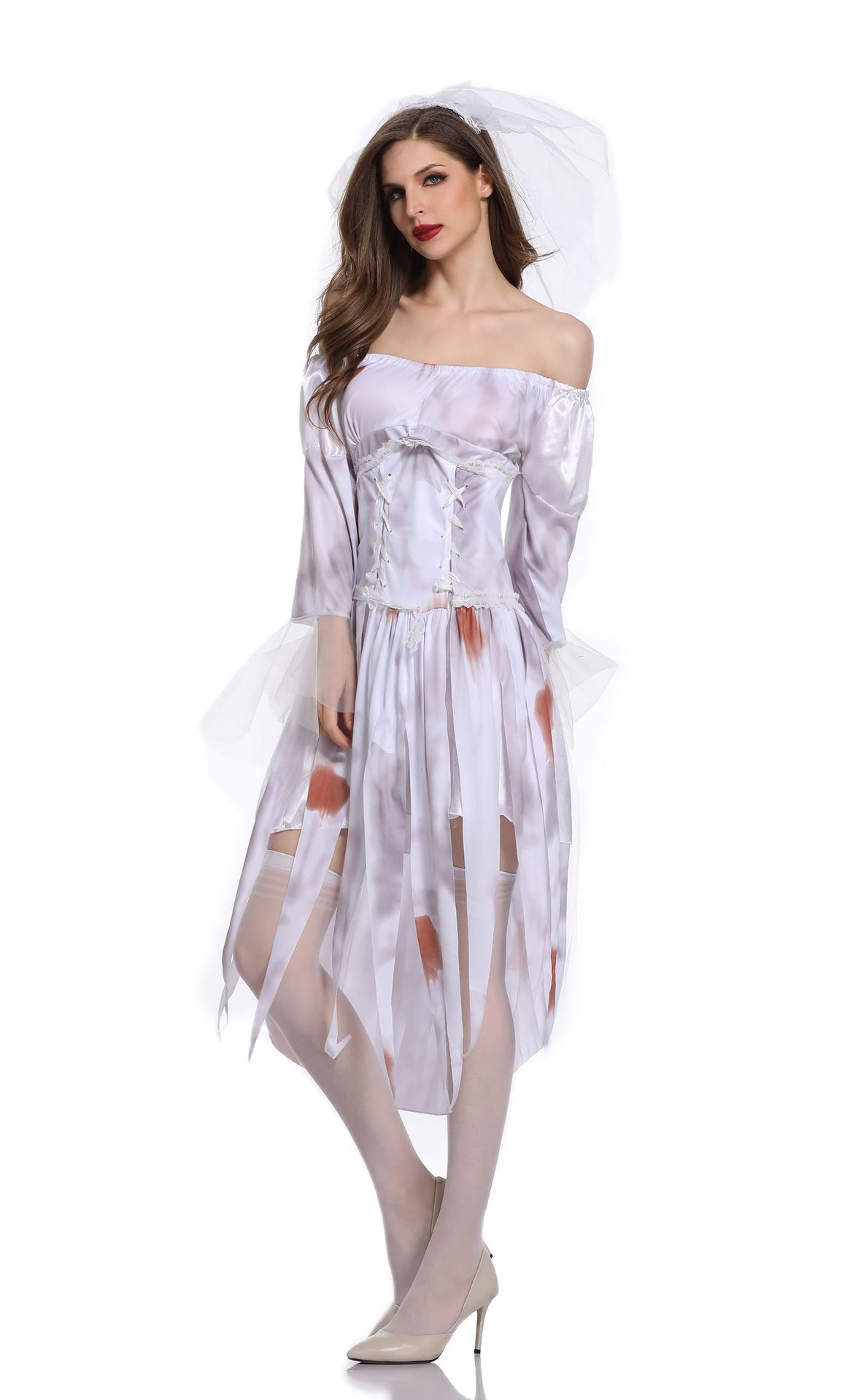 Woman in a distressed white bridal costume with brown stains, sheer veil, and off-shoulder neckline. She wears beige heels and stockings, posing on a white background.