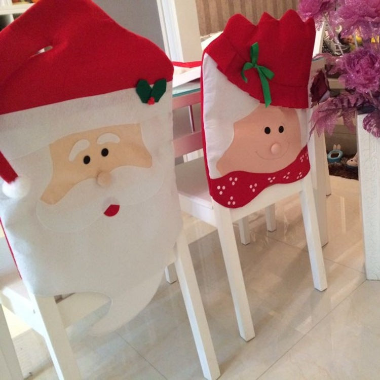 Festive chair covers designed as Santa Claus and Mrs. Claus in red and white felt add holiday cheer to white dining chairs. A purple Christmas tree is partially visible nearby.
