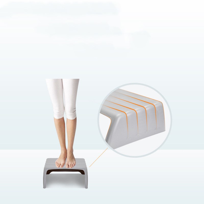 Person standing on a gray step stool with orange lines, wearing white pants. A close-up inset highlights the stool's surface design against a light background.