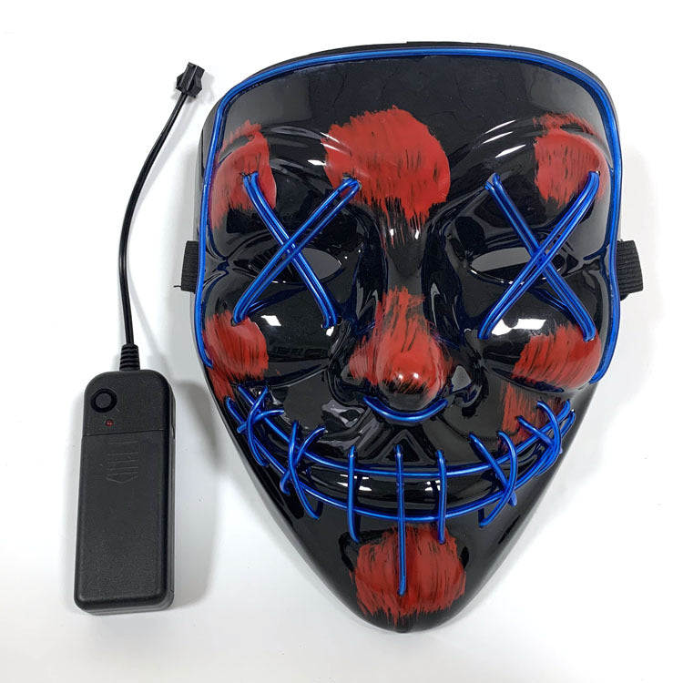 LED mask with black base, blue Xs on the eyes, a stitched mouth design, and red paint splatters. A small black battery pack with a wire is attached on the side.