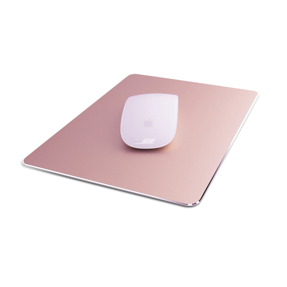 A sleek white wireless mouse on a metallic pink mouse pad. The pad has rounded corners and a minimalist design, accentuating the modern aesthetic.