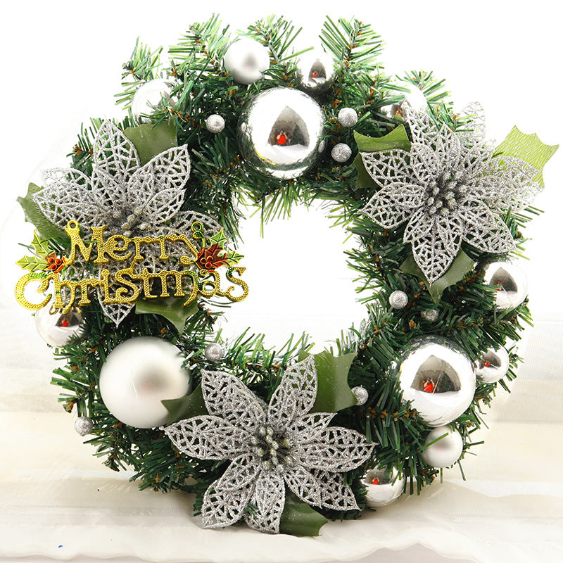 Festive Christmas wreath with silver baubles, glittery silver poinsettias, and green foliage. A "Merry Christmas" sign in gold with holly berries adds a cheerful touch.