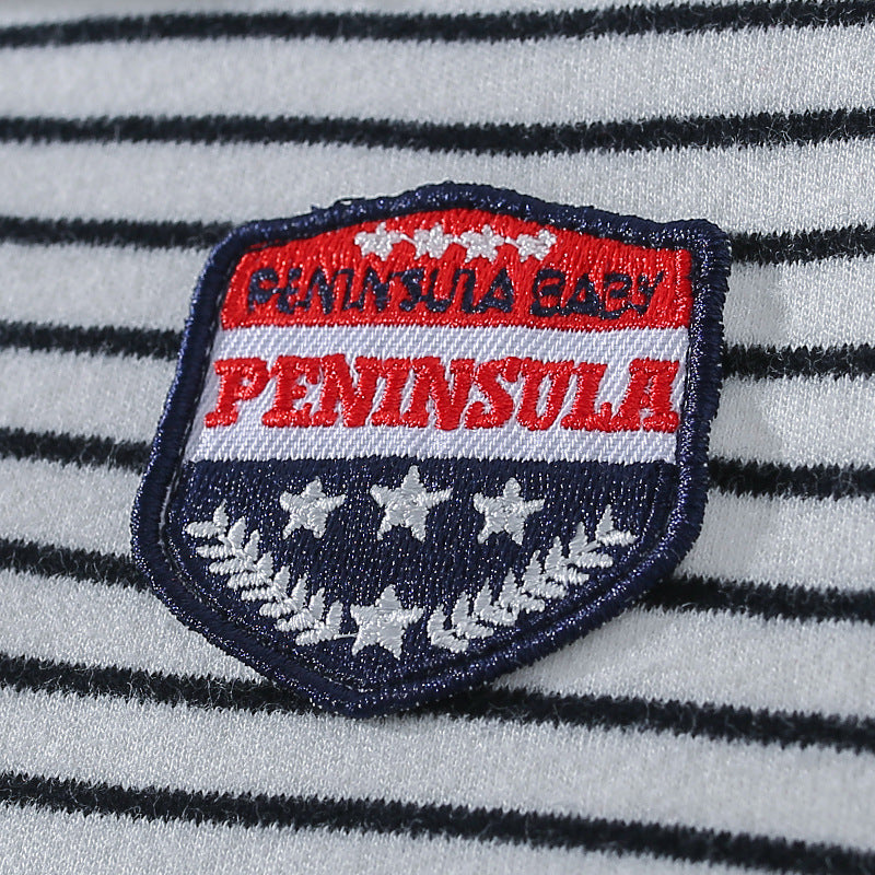 Striped fabric with a patch featuring the words "Peninsula Baby," red and white stripes, stars, and laurel leaves in blue and white.