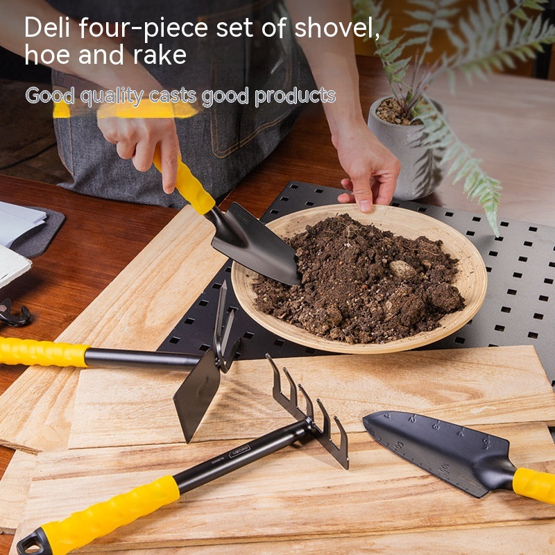 Four-piece gardening tool set with yellow-handled shovel, hoe, and rake on a table. A person is using the shovel to gather soil into a wooden bowl, with a potted plant nearby.