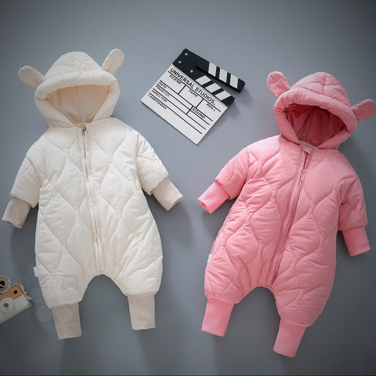 Two quilted baby onesies with bear-ear hoods; one is cream and the other pink. They are displayed on a gray surface along with a movie clapperboard.
