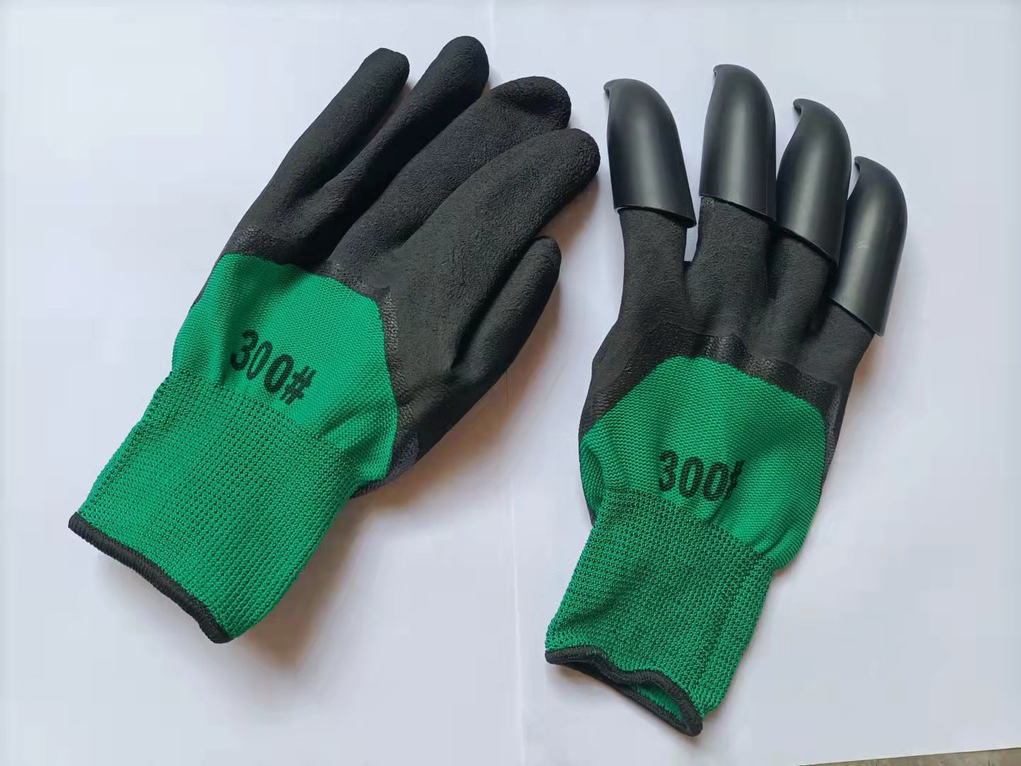 Green gloves with black palms and fingertips, labeled "300#". One glove has claw-like finger attachments; the other is plain. Both are displayed on a white surface.