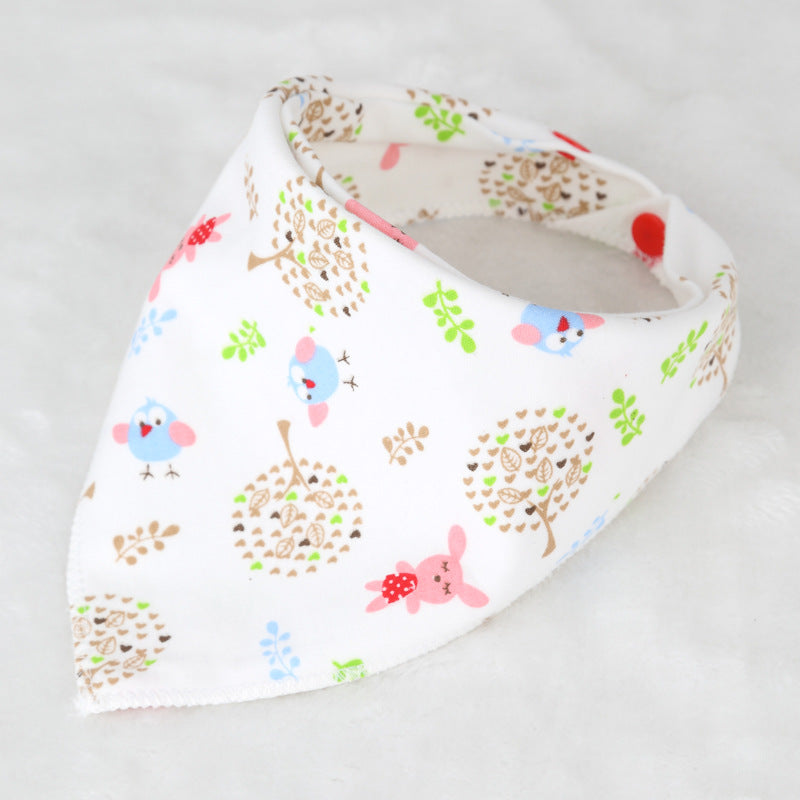 White baby bib with cute animal and tree patterns, featuring colorful birds, bunnies, and trees. The bib is folded in a bandana style and snaps closed with red buttons.