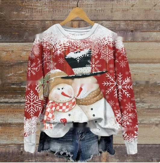 Red sweater with snowflake patterns and two hugging snowmen, one in a top hat and the other with a scarf. Paired with distressed denim shorts, displayed on a wooden background.
