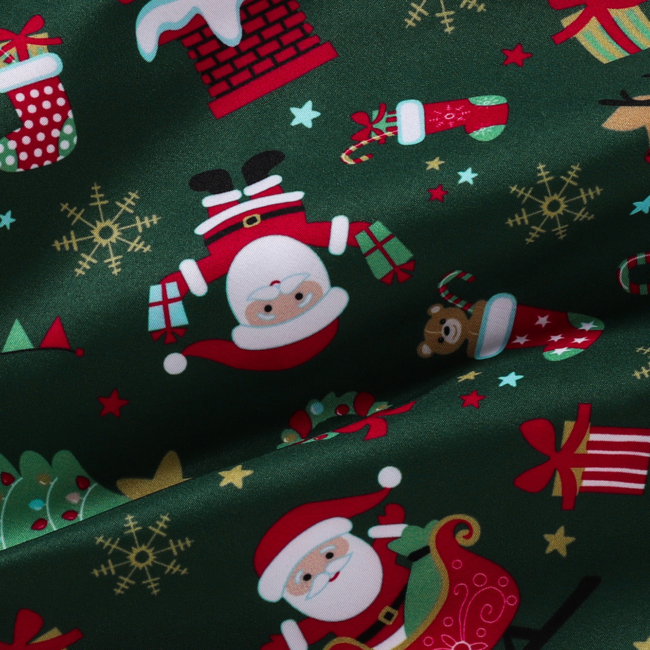 Festive green fabric with Santa, gifts, sleigh, stockings, and snowflakes. Playful Christmas-themed design with vibrant red, white, and gold elements on a dark backdrop.