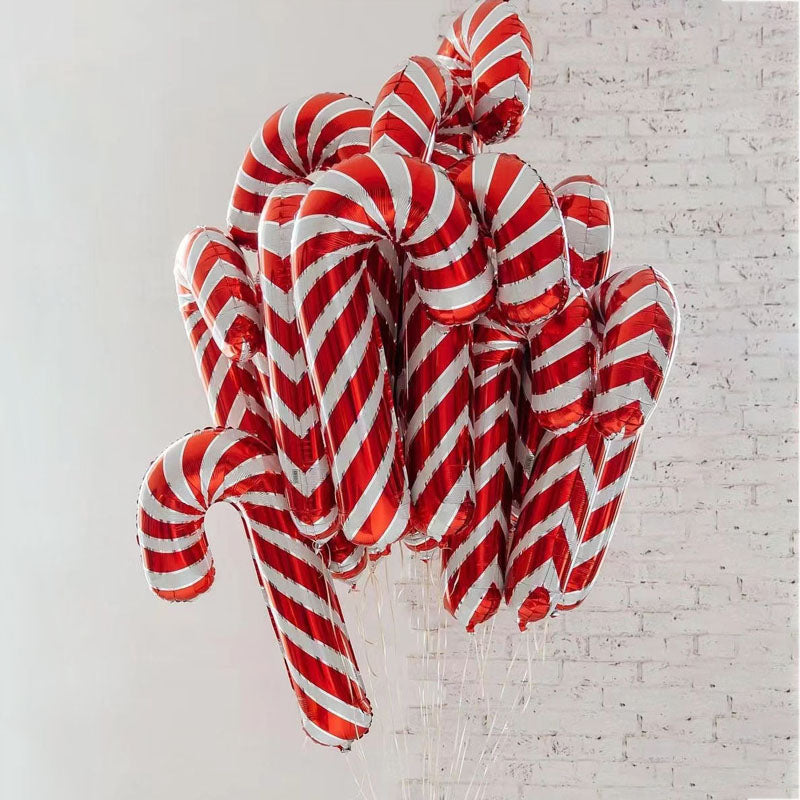 A cluster of candy cane-shaped balloons with red and white stripes is set against a light, textured wall, evoking a festive and cheerful holiday atmosphere.