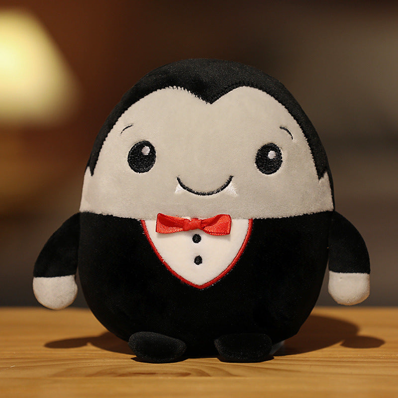 Cute plush toy resembling a cheerful penguin in a tuxedo with a red bow tie, resting on a wooden surface against a softly lit background.