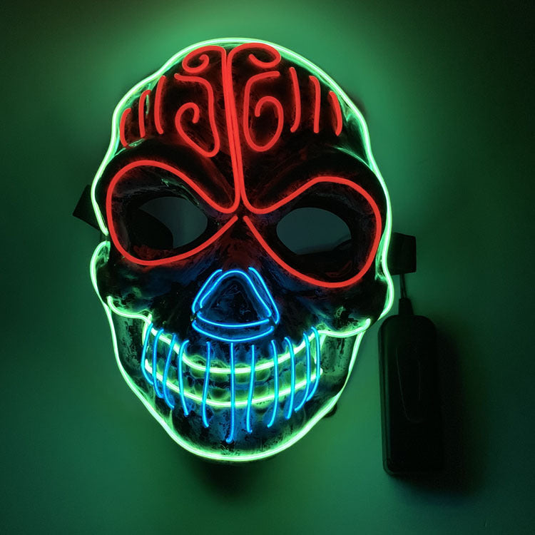 Neon skull mask glowing brightly, outlined with red, blue, and green lights. Intricate designs enhance the eerie appearance, set against a dark background.